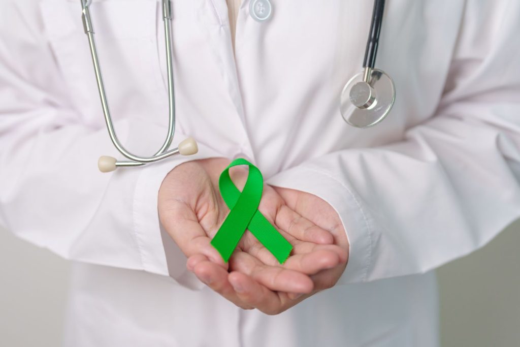 Doctor holding green Ribbon for world Mental Health Day, Liver, Gallbladders, bile duct, cervical, kidney Cancer and Lymphoma Awareness world cancer day