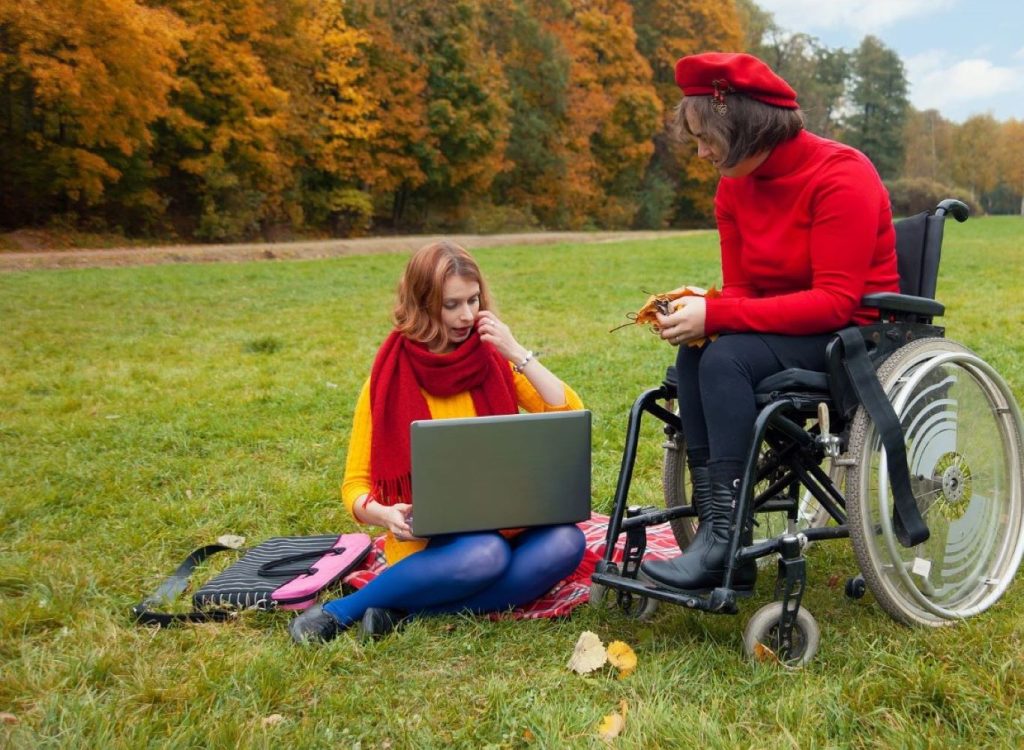 MS multiple sclerosis disability wheelchair two women in park with laptop