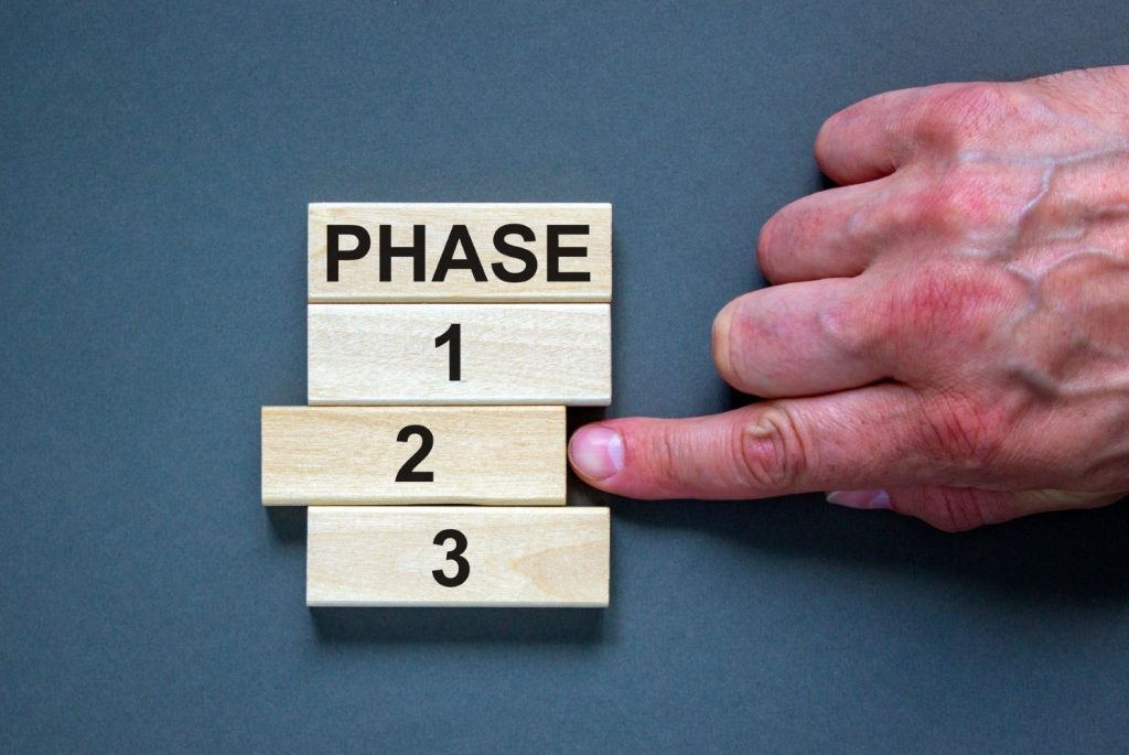 Wooden blocks form the words 'phase, 1, 2, 3,' on blue background. Male hand. Phases. Photo.