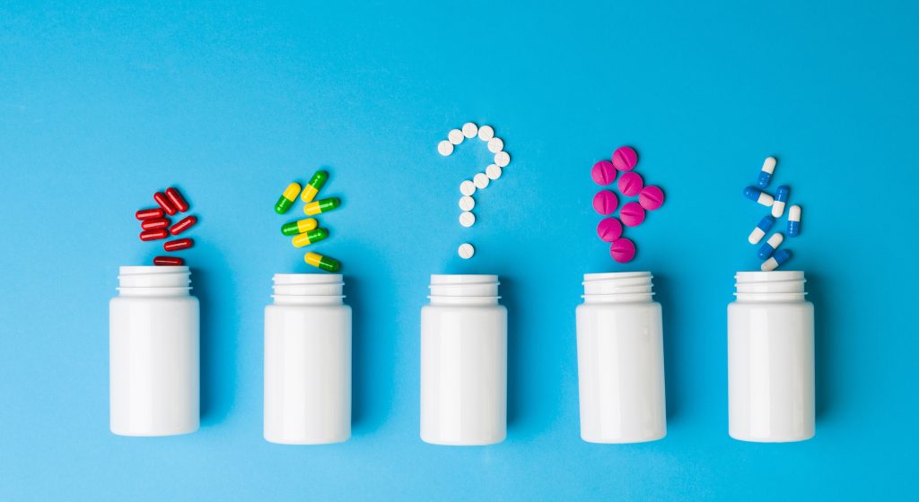 Various pills form question marks rising from white medicine bottles, medical questions, health questions, photo