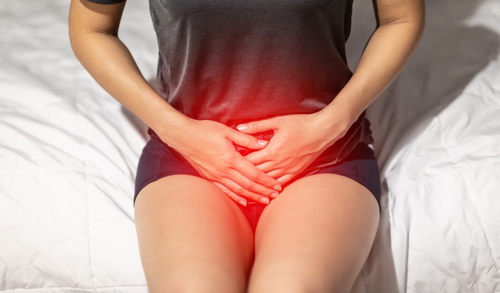 Woman with bladder or uti pain sitting on bed in bedroom, cystitis, bladder pain, urology, photo