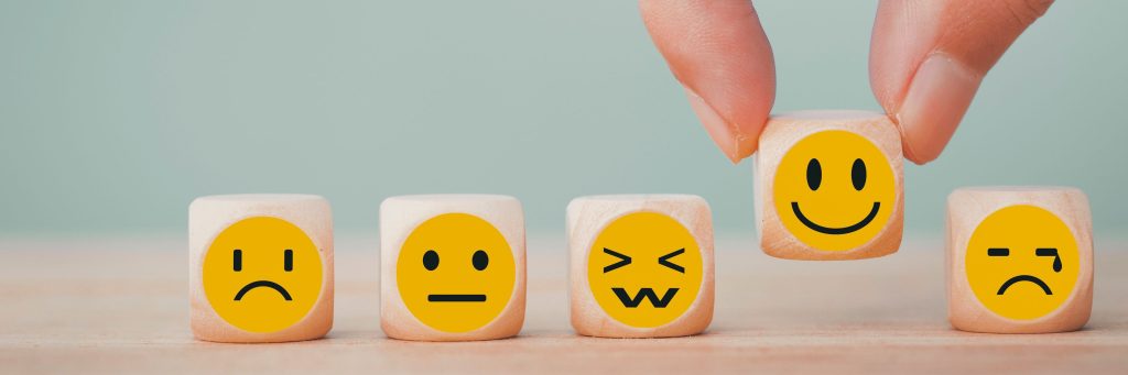 Hand chooses with happy smile face emoticon icons on Wooden Cubes, emotion regulation