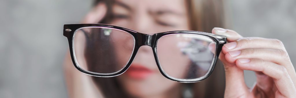 Asian woman holding eyeglasses having headache from eye blur vision