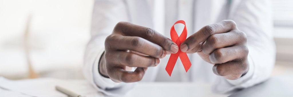 Close-up of African doctor holding red ribbon in his hands at hospital, HIV AIDS