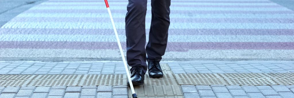 Visually impaired man using tactile tiles to navigate city, finishing crossroad, blind, blindness, crosswalk