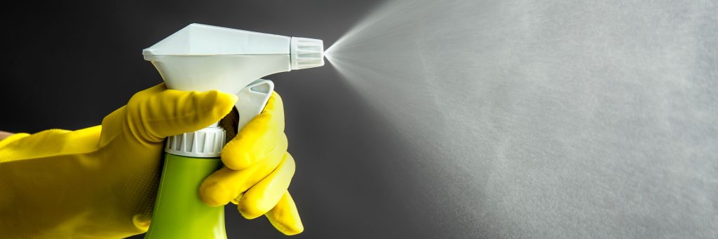 household cleaners, cleaning products, spray, Woman wearing yellow rubber gloves using green spray bottle and spraying liquid mist in air