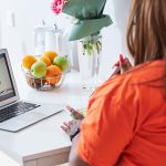 Lovely plus-size woman sitting in front of laptop in kitchen, obesity treatment, weight loss, online